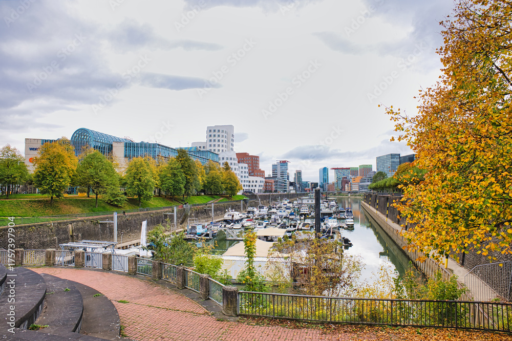 Obraz premium Gehry Designed Twisted Buildings Overlooking Busy Marina with Docked Boats and Autumn Trees in Düsseldorf Germany