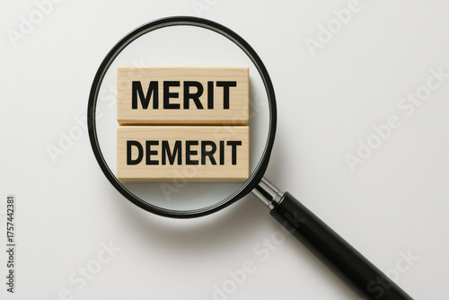 Magnifying glass highlighting wooden blocks with text merit and demerit on clean white background, symbolizing business pros and cons concept with clear focus and minimal style