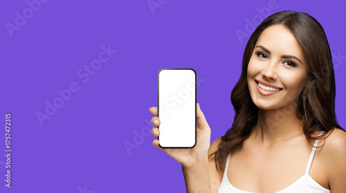 Portrait image - happy smile cute woman wear tank top casual cloth pointing show cell phone smartphone mobile phone cellphone with blank white mockup screen, isolate purple background. Online offer ad
