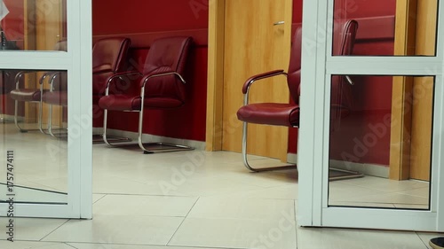 Bight corridor of a dental clinic with waiting chairs, doctors in protective clothing walking from room to room with patients. Human Health