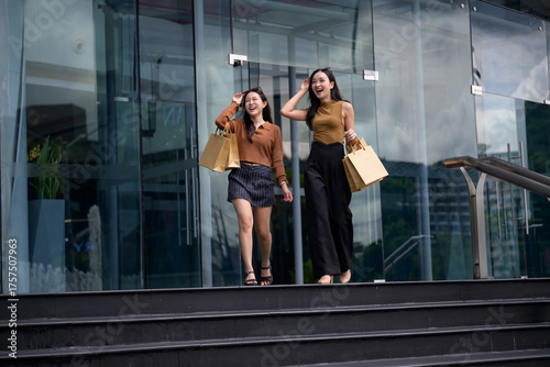 Happy young asian women shopping, walking down city stairs