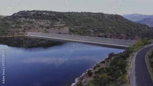 Aerial shot of the Salagou dam in France, showing the structure and surrounding red hills and blue waters. Check my portfolio for more Salagou Lake footage.