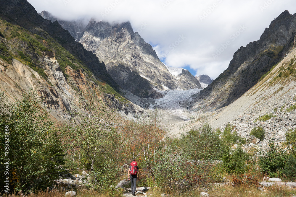 Fototapeta premium Hiker with Red Backpack Approaching Glacier, Svaneti, Georgia