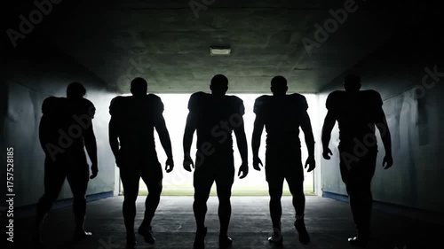 Silhouette of an American football team walking together through a stadium tunnel. Teamwork and unity concept.