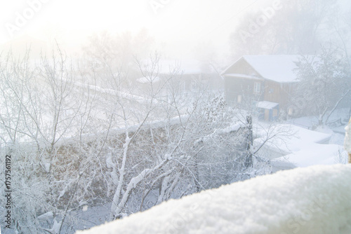 Old wooden house with frosted garden in Tomsk city during harsh Siberian winter. Concepts of Russian provincial heritage, northern craftsmanship, and rural authenticity in snowbound environment.
