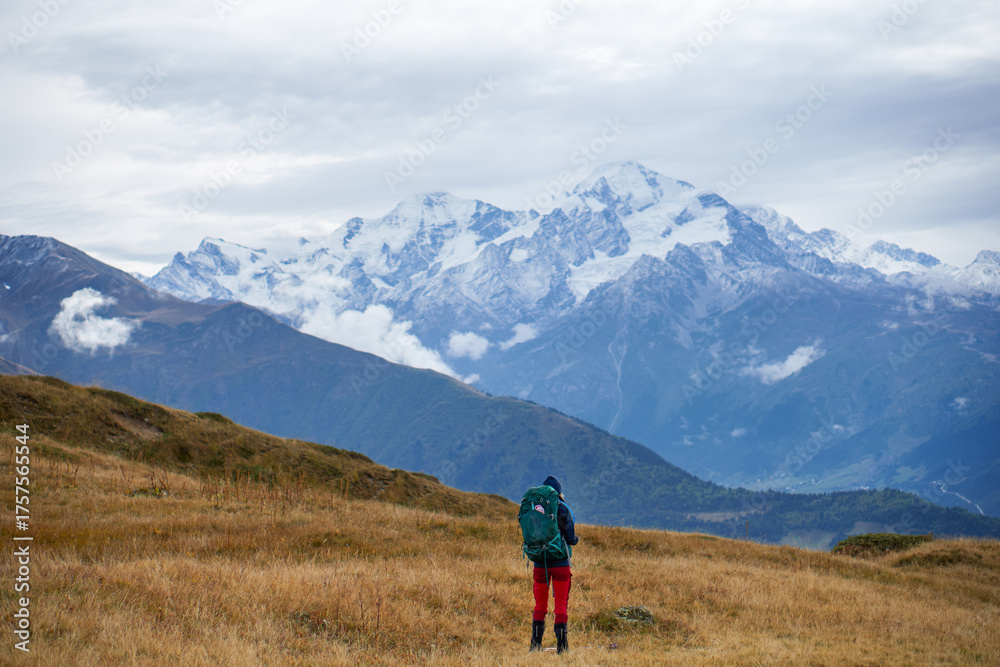 Obraz premium A hiker looking out over snow-capped mountains, Caucasus Mountains, Georgia