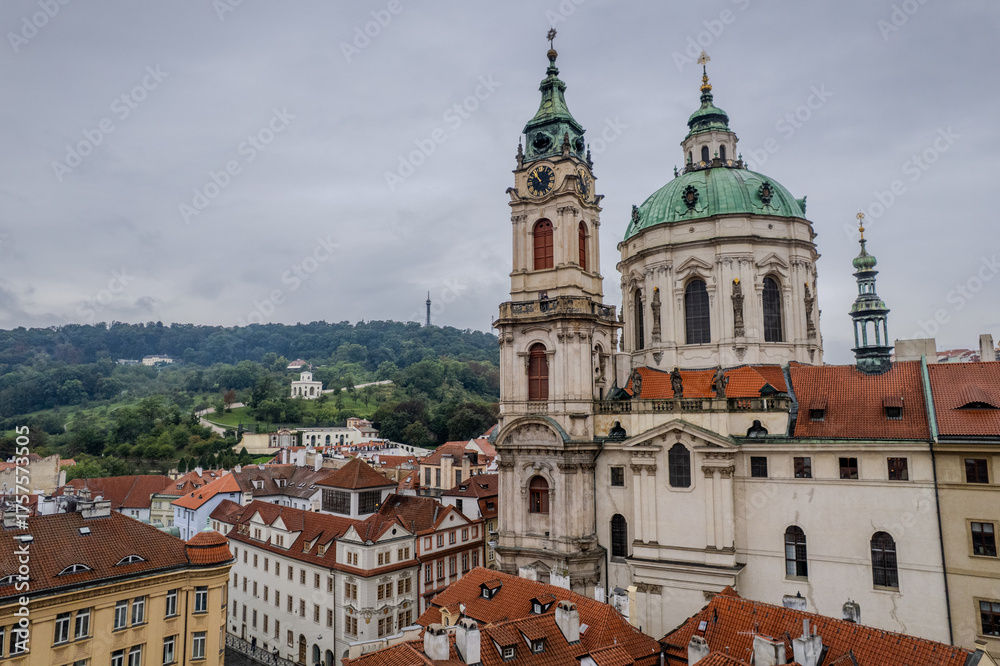 Fototapeta premium Beautiful aerial view St. Nicholas Church in the Lesser Town of Prague, Czech Republic — stunning baroque masterpiece surrounded by colorful old buildings and cobblestone streets