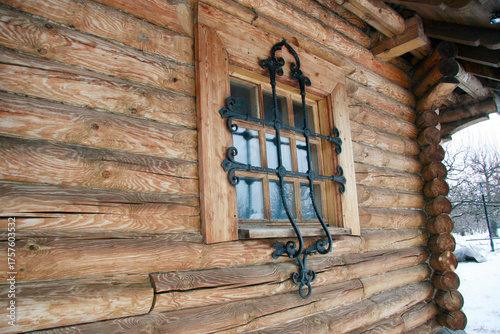 Log house with a cast-iron grated window in an old Russian town