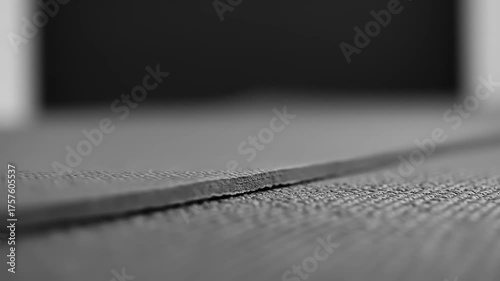 Close-up view of a textured surface with a slight edge curl, set against a blurred dark background