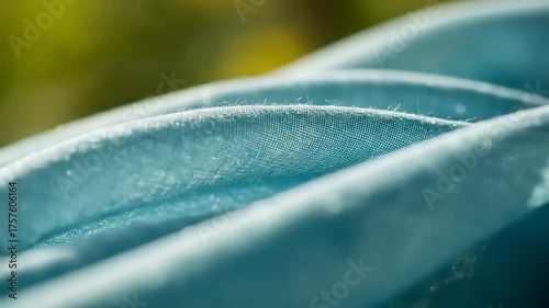 Close-up view of soft blue fabric folds with a blurred natural background, evoking tranquility