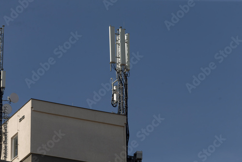 urban wireless infrastructure, rooftop cellular antennas with transmitters against city sky, urban rooftop cellular antennas mounted on buildings symbolizing wireless connectivity and infrastructure