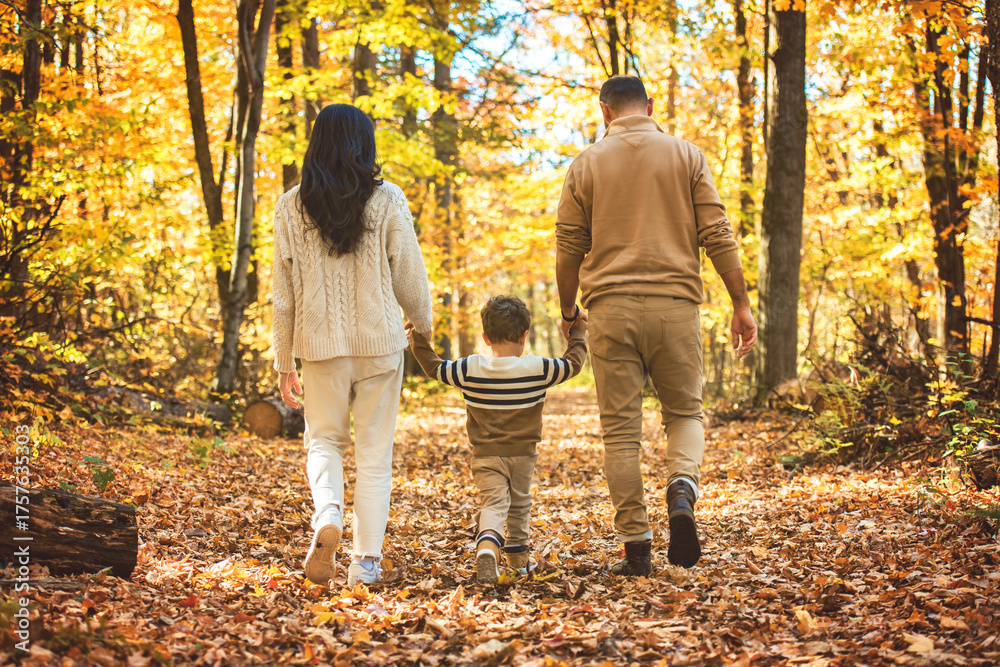 Fototapeta premium Beautiful young family on a walk in autumn forest