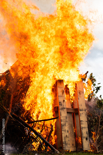 Close up of large local bonfire on grass field vertical view and intense burning.