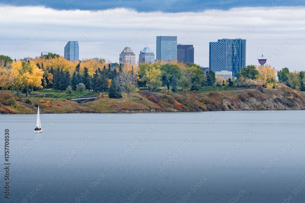 Obraz premium Lone sailboat on urban lake overlooking downtown autumn cityscape Calgary Alberta 