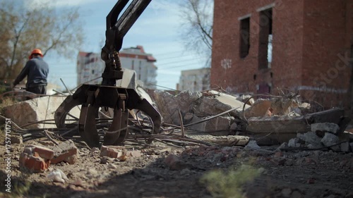 Excavator claw clearing debris after building demolition
