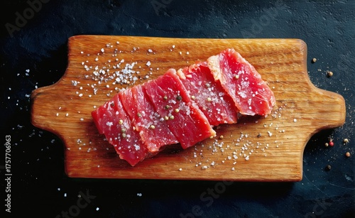 Freshly Sliced Beef on a Wooden Cutting Board With Coarse Salt and Pepper