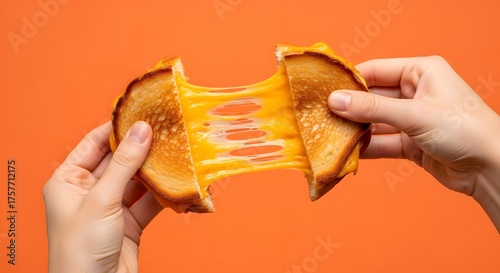 Hands pulling apart a grilled cheese sandwich with stretchy melted cheese against an orange background, showcasing its gooey texture.