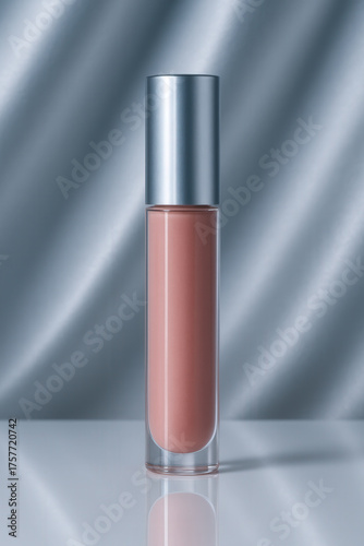 Elegant Nude Lip Gloss Tube on Reflective White Surface Against Silky Blue Curtain Backdrop
