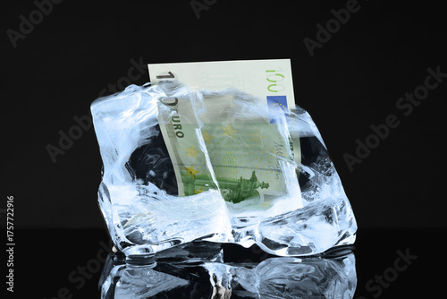 Euro bill in ice cube on black background. Frozen money