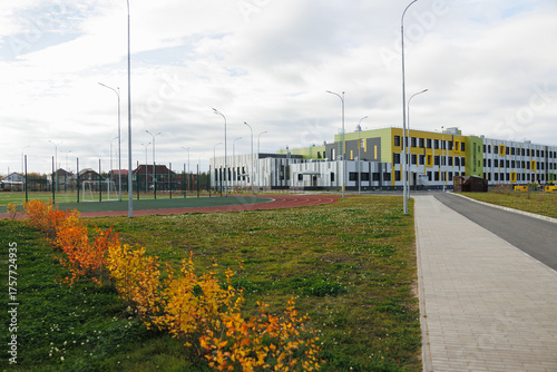 Modern community campus with pathway, green lawns and colorful shrubs