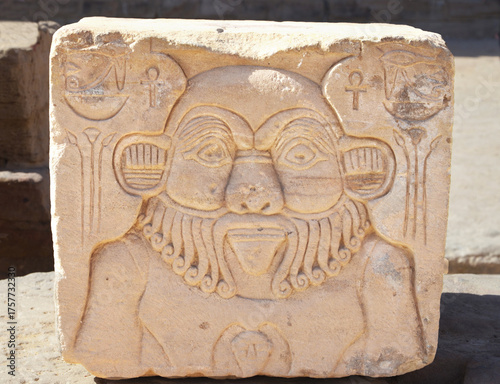 Relief of the ancient god Bes on a stone block of the temple of Philae at Aswan, Egypt