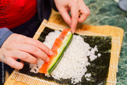 Hands Assembling Vegetable Maki Sushi Roll on Bamboo Mat