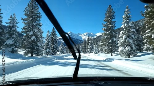 Driving through snowy winter landscape with evergreen trees and mountains