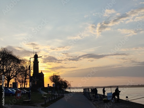 Lighthouse and Docked Boats at Harbor Entrance during Sunset.