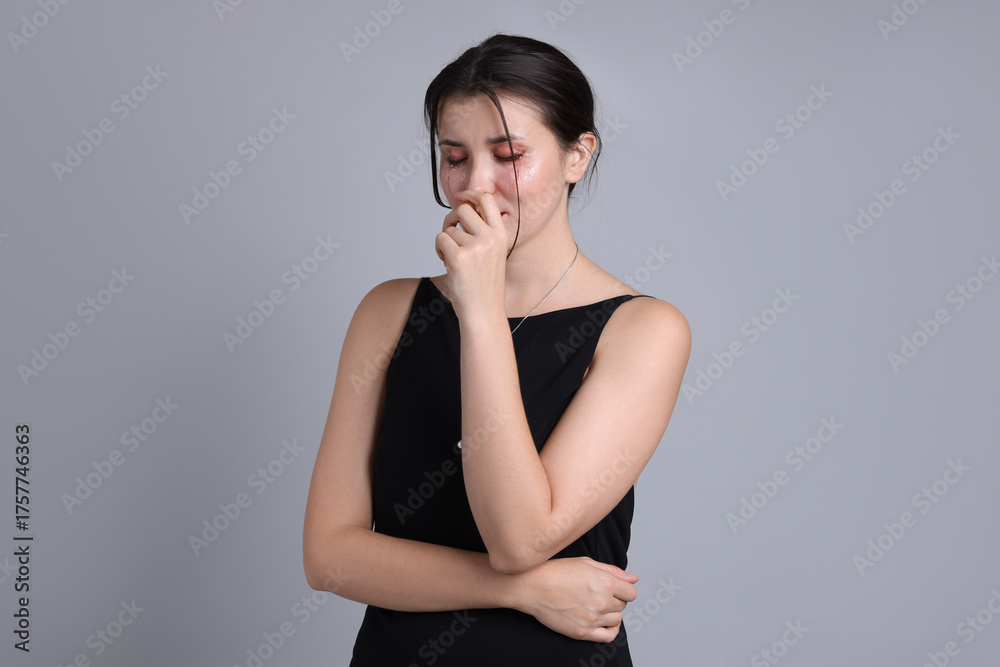 Fototapeta premium Woman in dress crying on grey background
