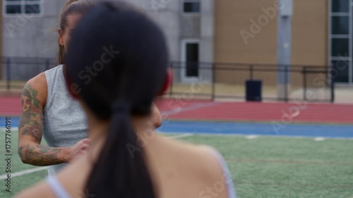 An athletic instructor passionately coaches her students on the field while holding a stopwatch.