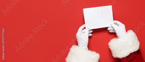 Fototapeta Naklejka Na Ścianę i Meble -  Santa Claus hands holding blank card on red background with space for text, top view