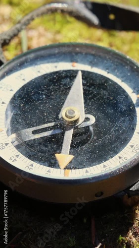 A Close-Up Video of a Vintage Compass Resting on Vibrant Green Moss in a Natural Forest Setting. The Compass Needle Swings Gently as It Finds North, Captured Under Warm Sunlight, Evoking a Sense of Ad