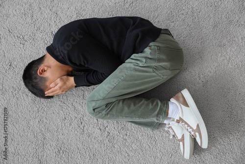 Sad young Asian man lying o...