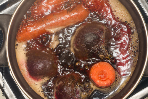 Top view of fresh carrots and beets in a pot of boiling water.