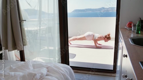 Middle aged woman doing morning yoga famous Surya Namaskar exercise on sea view terace hotel room. Poses like Adho Mukha Svanasana, Ashtanga Namaskara, Bhujangasana making your body more flexible.
