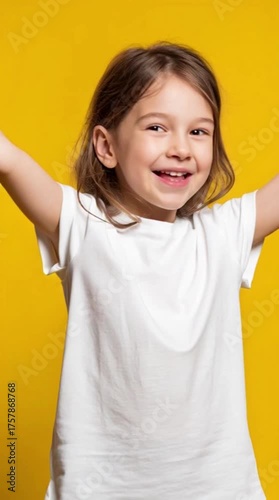 Satisfied child. Like gesture. Good idea. Approval sign. Vertical portrait of happy enthusiastic cheerful girl in white t-shirt showing thumbs up smiling isolated on yellow copy space background