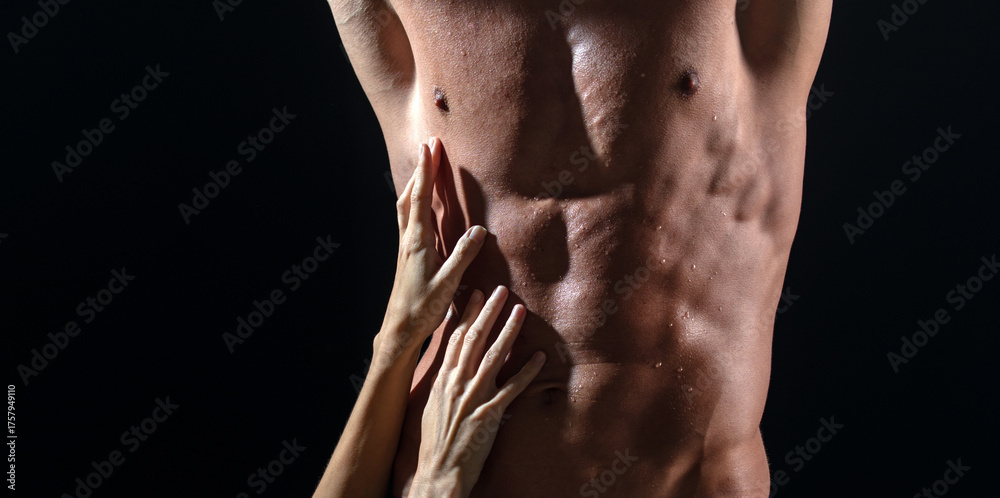 Fototapeta premium Sexy male model with female hand. Perfect abs shoulders biceps triceps and chest. Strong man with muscular body. Sexy male bare torso. Metrosexual mans naked.