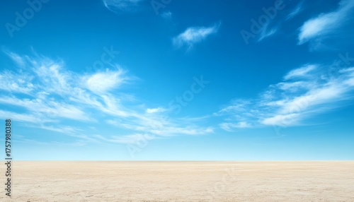 Fototapeta Naklejka Na Ścianę i Meble -  Vast expanse of pale sand under a vibrant blue sky with wispy clouds