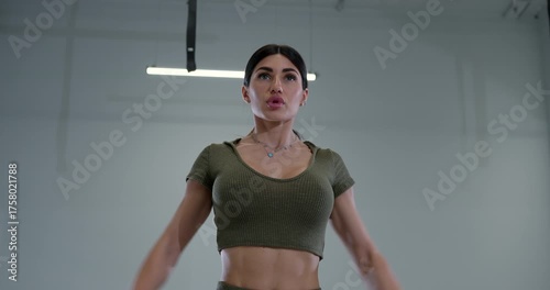 athletic woman engages in lateral dumbbell raises in a modern fitness center. She shows focus and determination during her workout showcasing her strength and fitness goals.