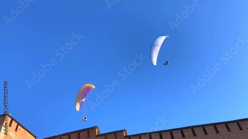 NIZHNY NOVGOROD, RUSSIA - MAY 23, 2024: Paragliders above the Kremlin and the Chkalov Stairs. Gliding through a flawless blue sky, serene and endless, paragliders dance in perfect harmony and grace