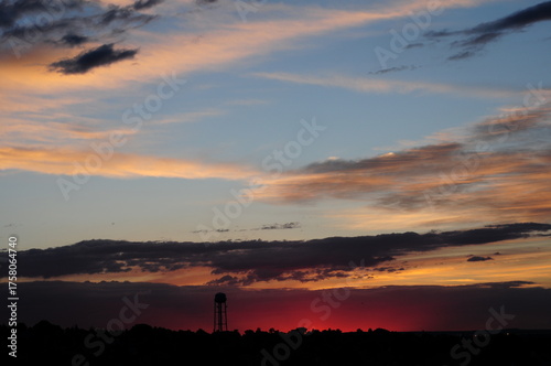 Vibrant orange and blue evening sky with beautiful clouds at dusk over the city landscape by the river