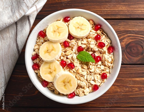Overhead view of oatmeal bowl with banana, pomegranate, and mint