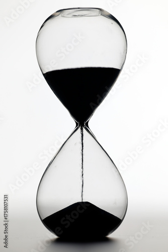 Foto Classic glass hourglass with dark sand captures concepts of impermanence, countdown, patience, and passage of life
