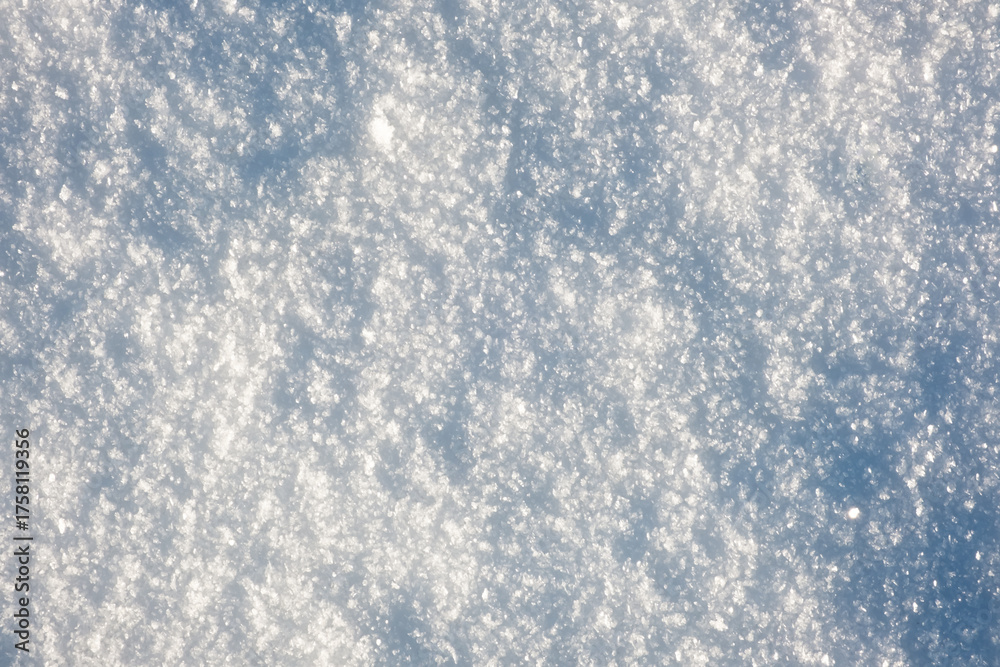 Obraz premium Close-up snowflakes texture. Winter background. Small depth of field. White snowy surface with shiny ice crystals. Frozen water condition. Beauty in nature. December details. Sunny frozen weather day