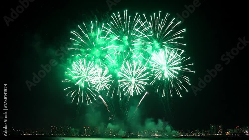 Vibrant Green Fireworks Illuminate the Night Sky Above a Waterfront City Skyline
