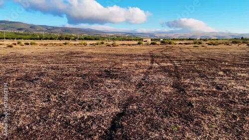 An aerial shot of a vast and barren agricultural field with textured soil under a wide sky with distant mountains a depiction of the stark beauty of cultivated land out of season