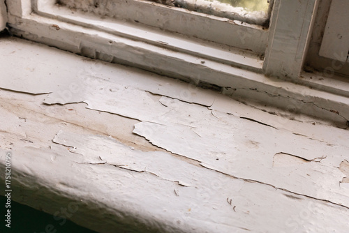 Fotografía Window sill of an old house reveals significant damage with peeling paint and discoloration