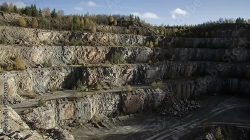Large open pit mine with layered rock formations and distant trees