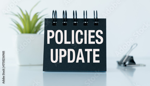 A black spiral bound notebook with the word Policies Update written on it.