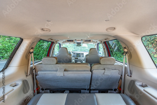 Rear two row beige leather bench seats, interior of an older 2004 American 4x4 family suv truck.   Shown in natural daylight, highlighting clean and well-preserved cabin details, speakers, armrests 